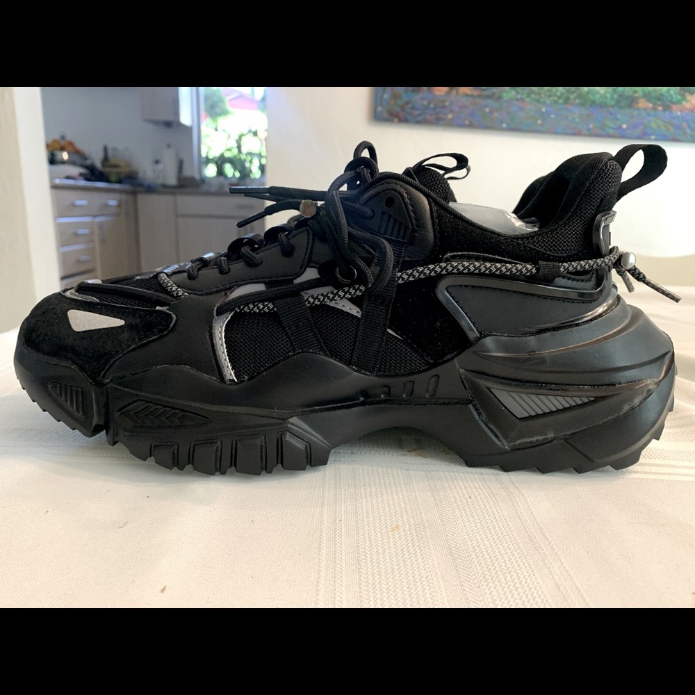 Black mens athletic shoe worn once by luxury fitness trainer for photo shoot.